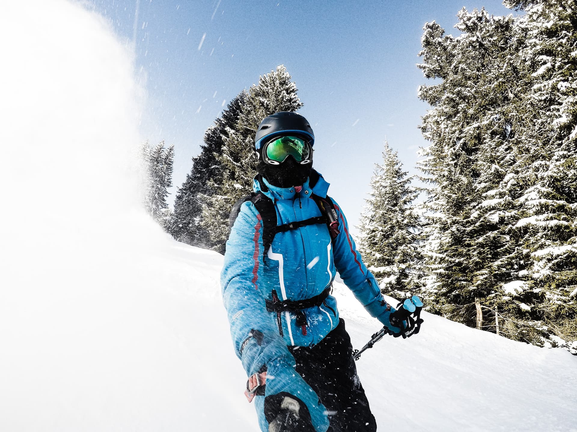 Skier in blue jacket taking selfie while skiing down hill