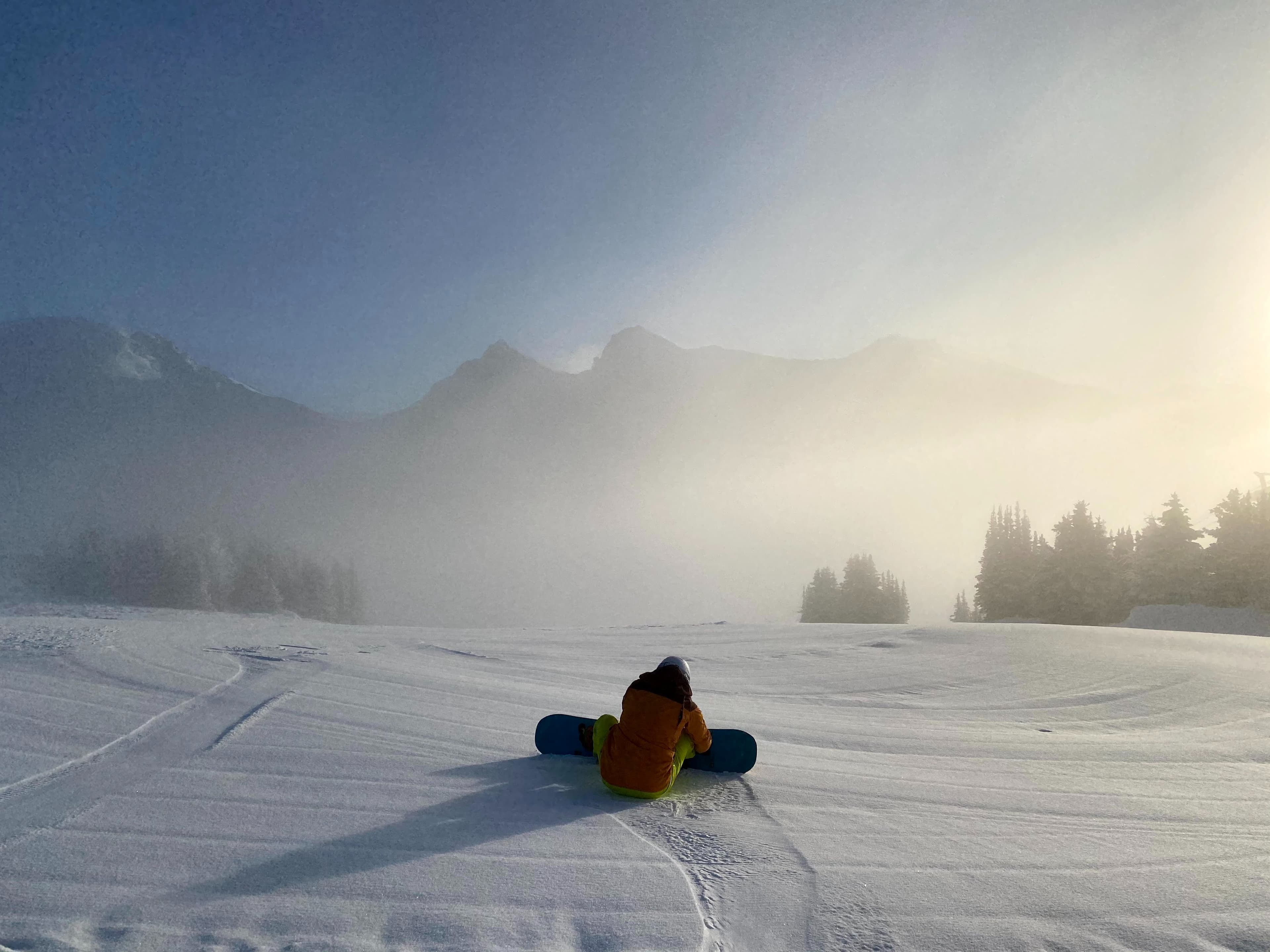 Snowboarder getting ready to drop into ski slope on a misty day
