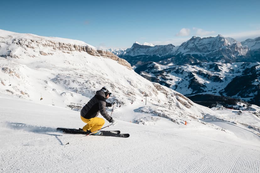 Skiiers skiing down Italian ski slope on sunny day in dolomites